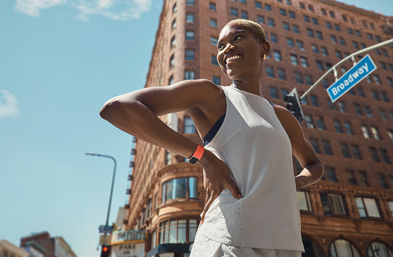 Woman running in the city with Fitbit device