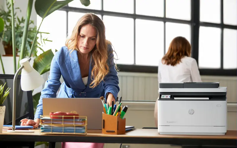 HP printer on desk printing out a paper.