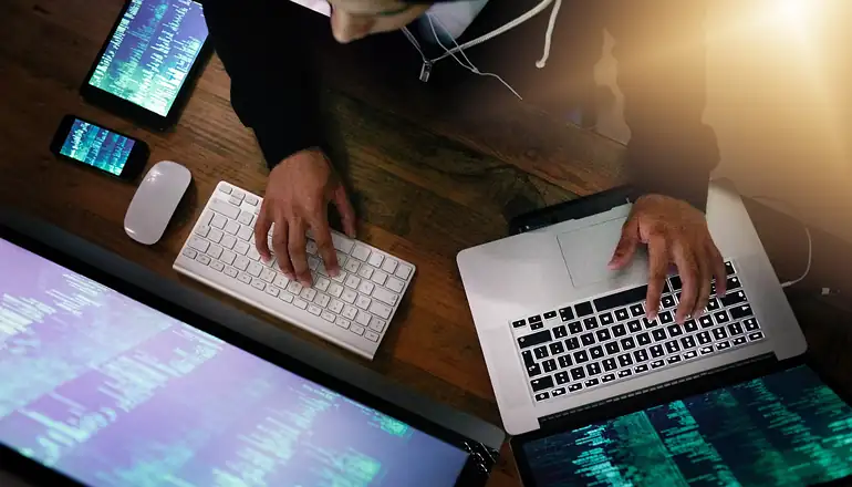 Man working on two laptops.
