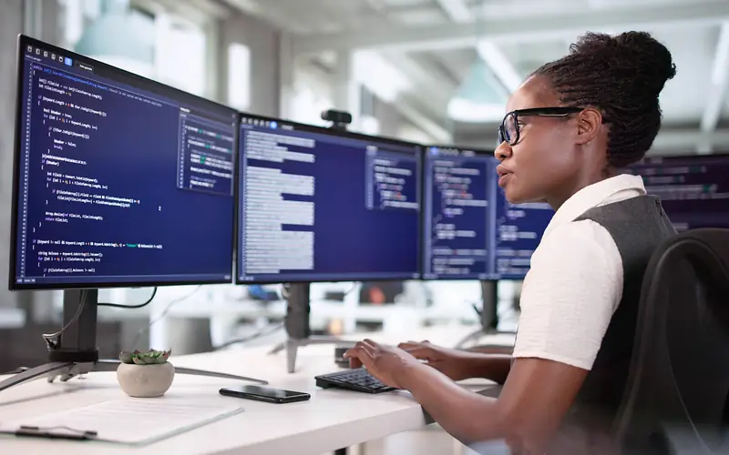 Girl coding on a desktop at work.