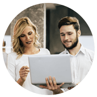 Two business colleagues stand in office hallway with laptop computer