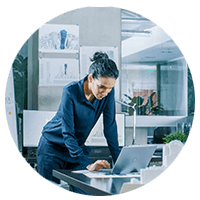 Businesswoman standing working on laptop computer in open office