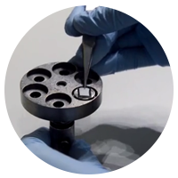 Gloved hand placing sample in scientific equipment being used to find innovations.