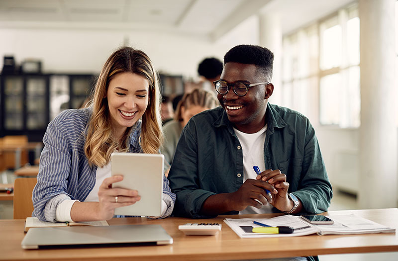 Two higher ed students studying with technology device