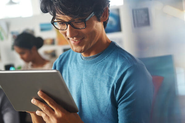 Businessman using tablet computer in office and smiling