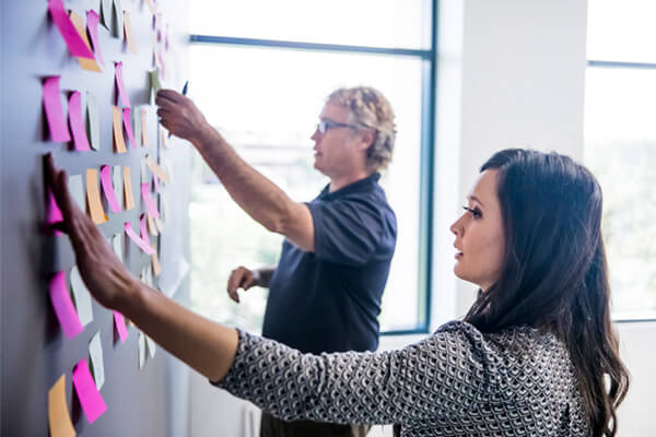 Collaboration team putting ideas up on the wall using postit notes