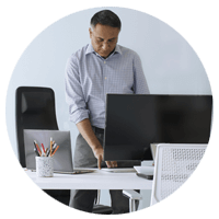 Business man standing while at desk typing on Microsoft laptop