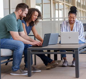 Group of Insight employees collaborating on laptops outside