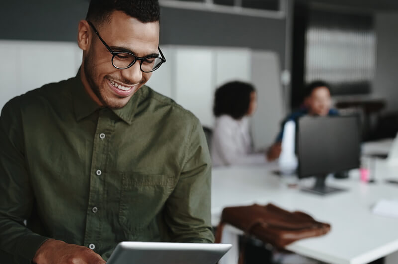 Happy entrepreneur utilizing a tablet in a contemporary workplace connected to the cloud.