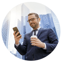 Businessman using VoIP on smart phone outside, coffee in hand and building skyline in background