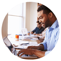 Casual dressed businessman using laptop at desk in front of window.