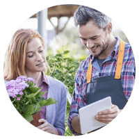 Retail flower shop employee using tablet computer to look-up inventory with client