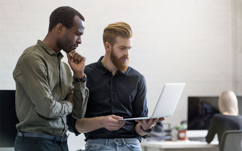 Two businessmen standing holding laptop computer