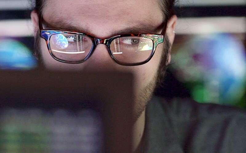 Man with eyeglasses in front for monitor