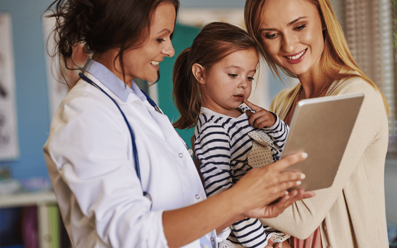 Doctor holding tablet device to mother and daughter  patients