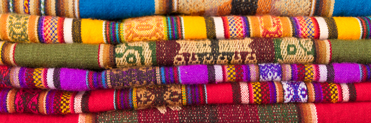 Close up of multicolored artisan rugs piled on top of each other