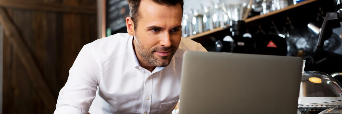 A new small business owner setting up cloud computing software on his laptop