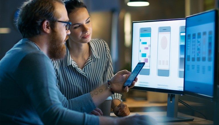 Two designers work on mobile app development on computer