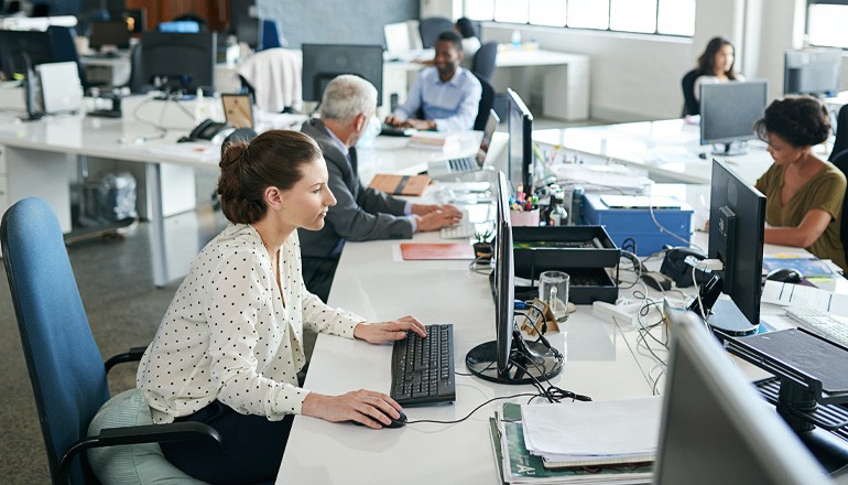 Businesswoman working in open office on desktop computer
