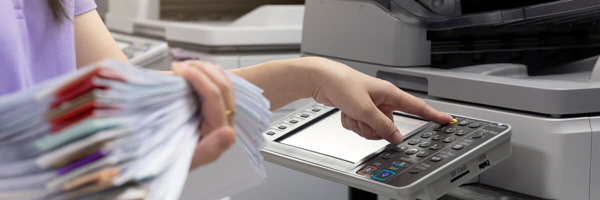 Healthcare professional holding a stack of patient records while using a Multi-function printer. MFP printers, HP Printers