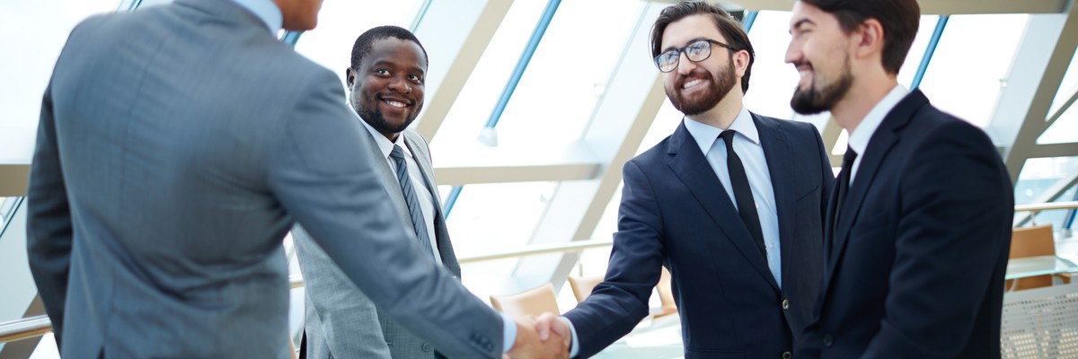 Photo of four business professionals shaking hands 