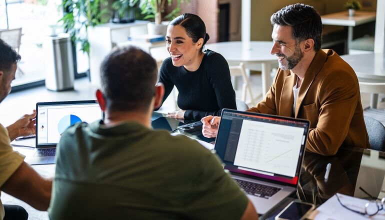 People smiling around computers at meeting