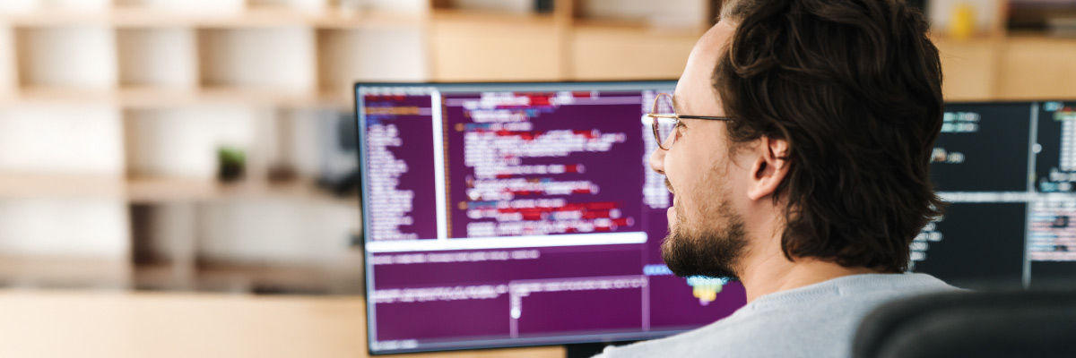 Build vs. Buy in the Autonomous Agent Era Man smiling at his desktop.