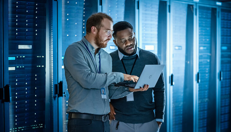 Two men in data center on a laptop