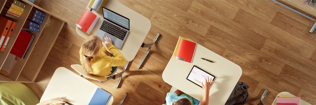 Top down view of students working on various devices in classroom setting