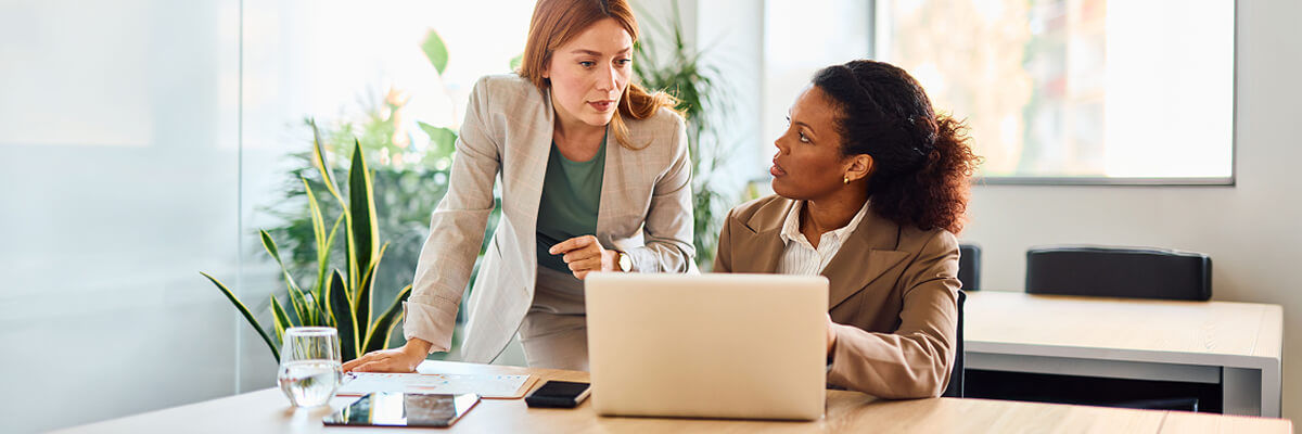 Two people having a convo with a laptop on desk