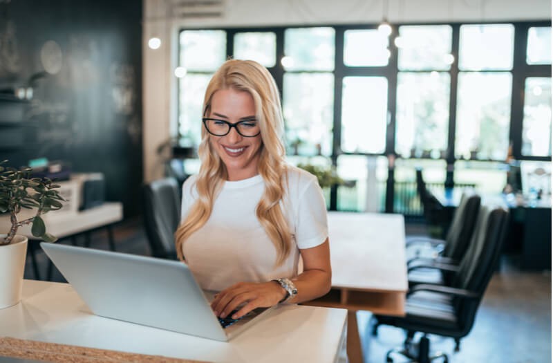 Smiling businesswoman on laptop computer in open office