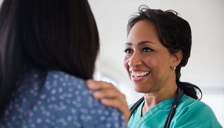 Smiling doctor puts hand on shoulder of patient