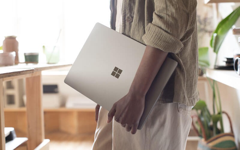 Man in small retail business holding Surface device in hand