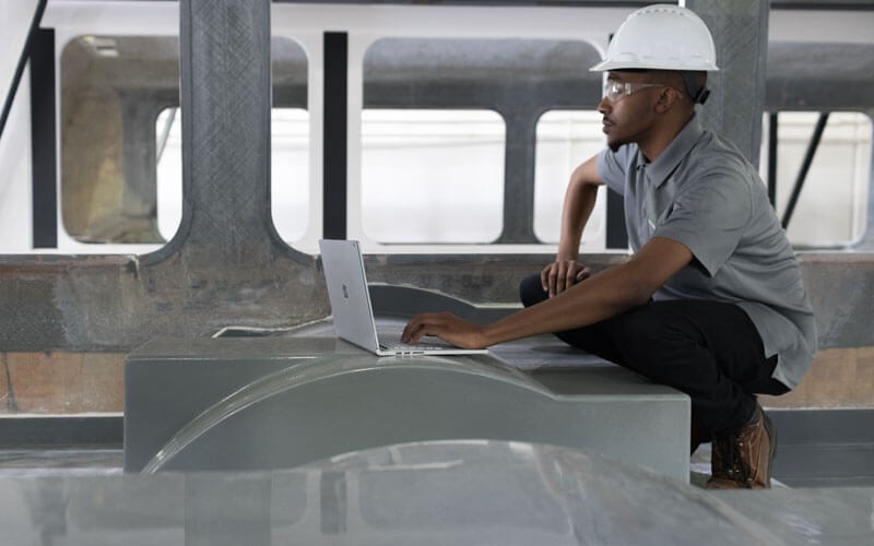 Man in hard hat works in manufacturing industry with Surface device