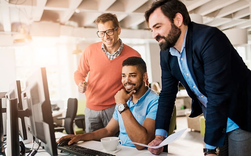 Leverage modern desktops Three business colleagues gather around desktop computer