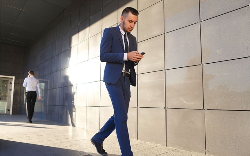 Business professional walking using mobile phone