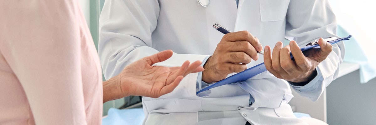 Doctor holds up clipboard and pen while sitting next to patient