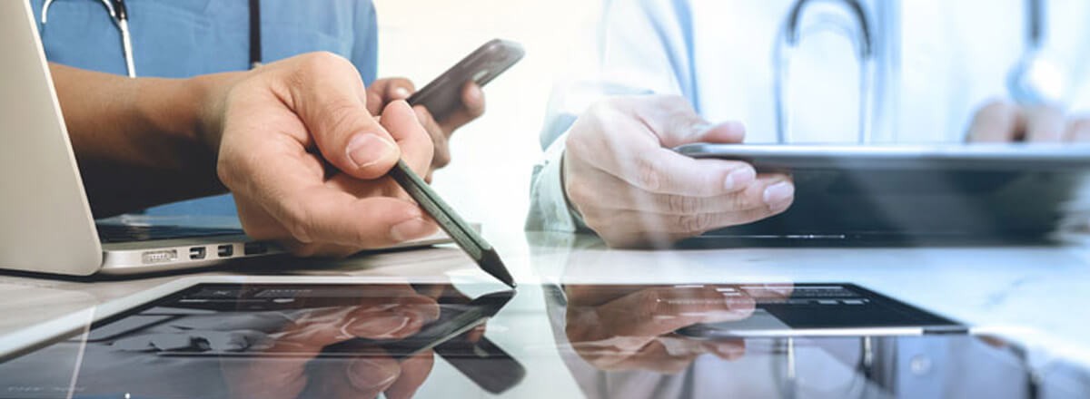 Two doctors using laptops and tablet devices