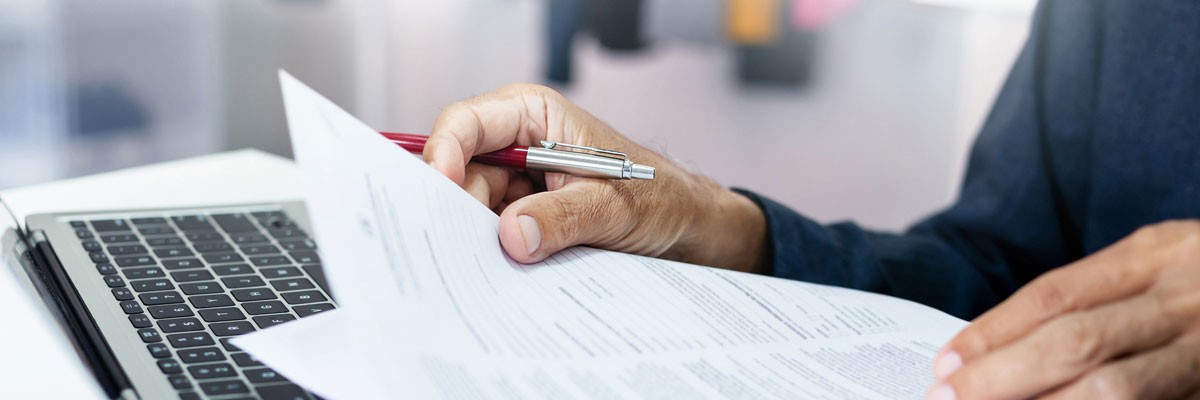 Close up of financial analyst looking over insurance information next to laptop