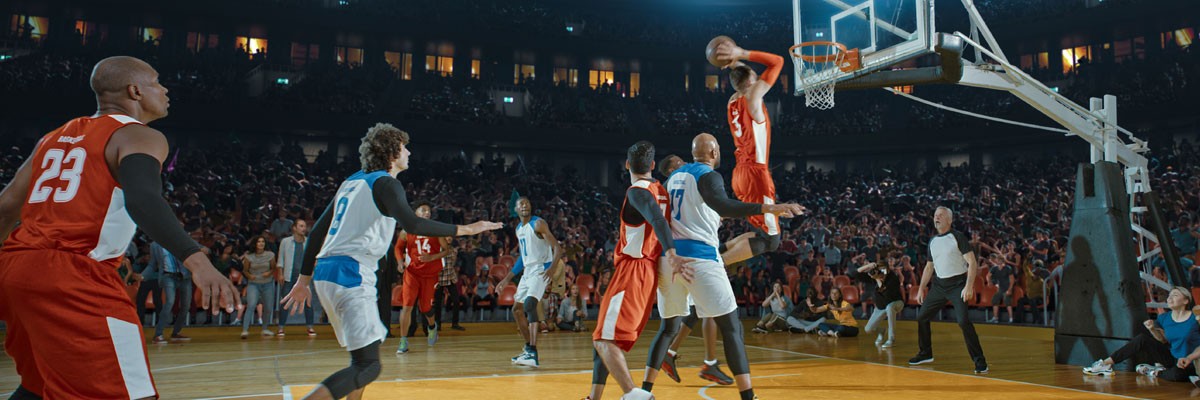 Basketball team plays on court with someone making a basket in the background