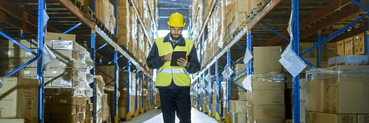 Man with tablet works in distribution center warehouse