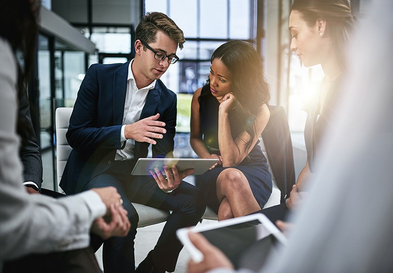 Group of business professionals having meeting around tablet computers