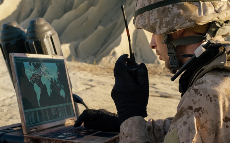 Military person using military technology in field Military person using military technology in field