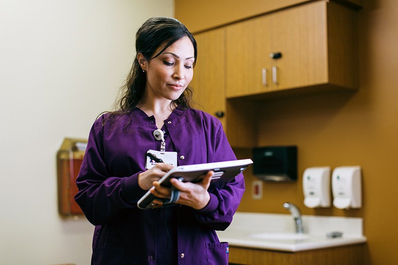 Nurse on mobile device looking at patient data.