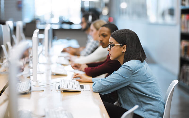Cloud foundation for higher ed Students working on technology devices in library