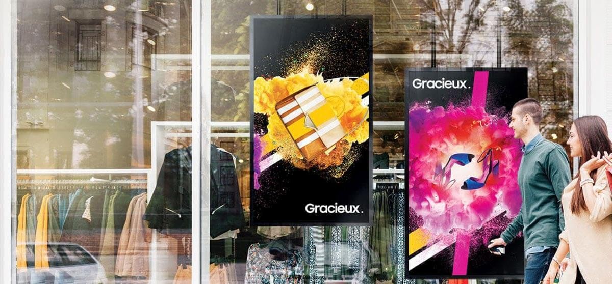 A man and woman walk by a retail storefront with an advertisement for an LED display technology