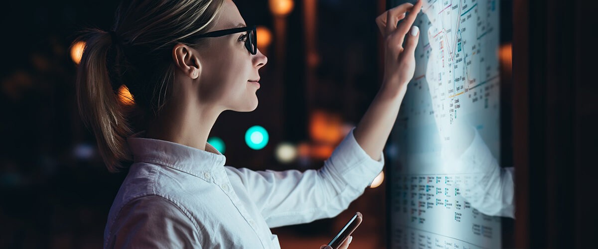  Woman checks bus route on digital touch display in modern city.
