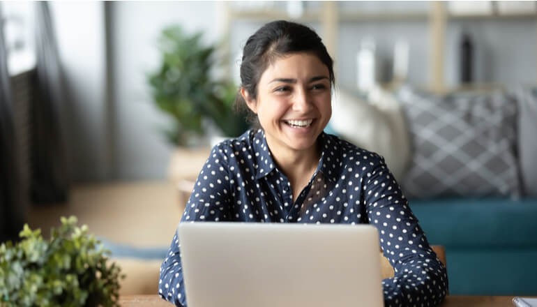 Woman smiling working at laptop in home environment