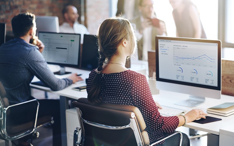 Open office with employees on monitor and desktop