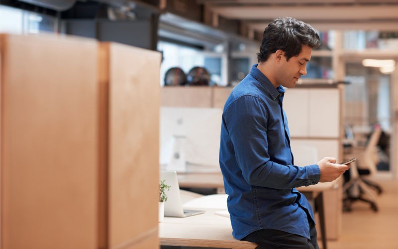 Converged security solution Male employee on mobile device in open office